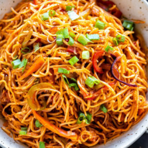 "A bowl of steaming noodles garnished with fresh vegetables, herbs, and a flavorful sauce, served as a delicious and comforting dish."