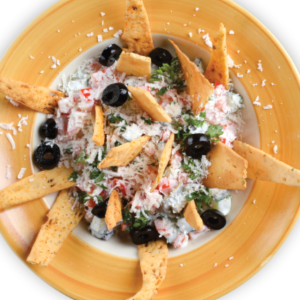 A plate of crispy nachos topped with melted cheese, jalapeños, sour cream, and a sprinkle of fresh cilantro, ready to be enjoyed."