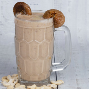"Delicious Kaju Anjeer Thickshake made with cashews and figs, served in a glass with a creamy texture, topped with nuts and figs."