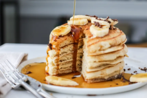 "Stack of fluffy pancakes drizzled with syrup, topped with fresh berries, and a dollop of whipped cream."