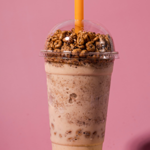 "A refreshing milkshake served in a tall glass, topped with whipped cream, colorful sprinkles, and a cherry, with a straw on the side."