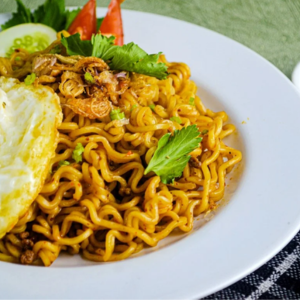 "A bowl of steaming noodles garnished with fresh vegetables, herbs, and a flavorful sauce, served as a delicious and comforting dish."