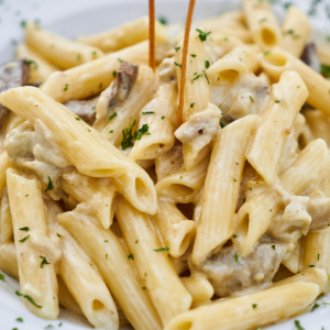 "A plate of creamy pasta topped with fresh herbs, grated cheese, and a rich sauce, served in a beautifully arranged dish."